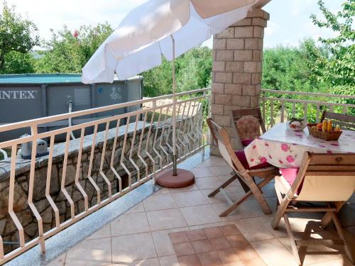 een tafel en stoelen op een balkon met een parasol bij Apartment Mirjana-1 by Interhome in Ružići