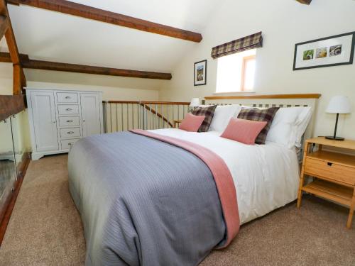 um quarto com uma grande cama branca com almofadas cor-de-rosa em The Barn em Harrogate