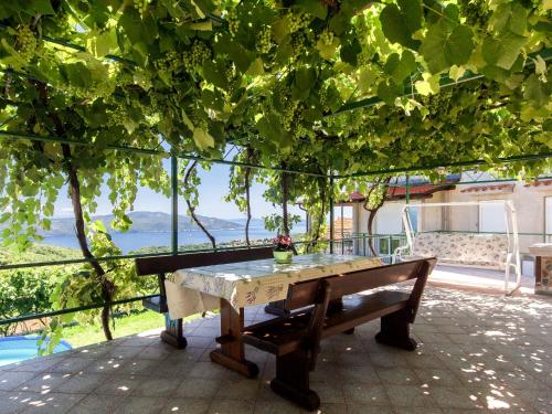a wooden bench sitting under a tree with a table at Apartment Johan - MOD117 by Interhome in Brseč