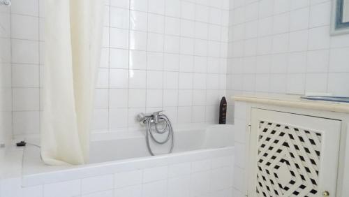 a white bathroom with a tub with a shower curtain at Quinta Velha Village - Apart. T1 in Cabanas de Tavira