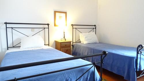 two beds in a room with blue sheets at Quinta Velha Village - Apart. T1 in Cabanas de Tavira