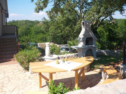 a picnic table and a fireplace in a yard at Apartment Urdih-2 by Interhome in Malinska