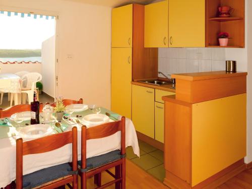a kitchen with a table and yellow cabinets at Apartment Barbara - PUT121 by Interhome in Punat