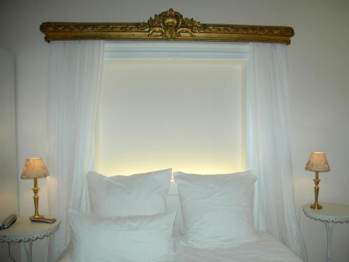 a white bed with white pillows and a window at Hotel Goldenes Kreuz in Regensburg