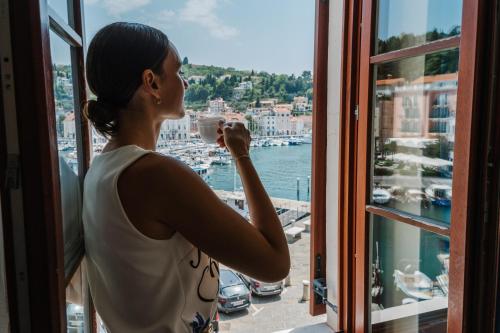 a woman taking a picture of a harbor from a window at Vila Piranesi Apartments - Parking included in Piran