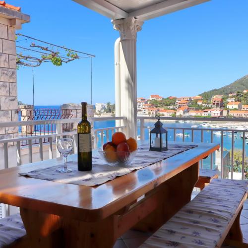 a table with a bottle of wine and fruit on a balcony at Apartments Peselj in Smokvica