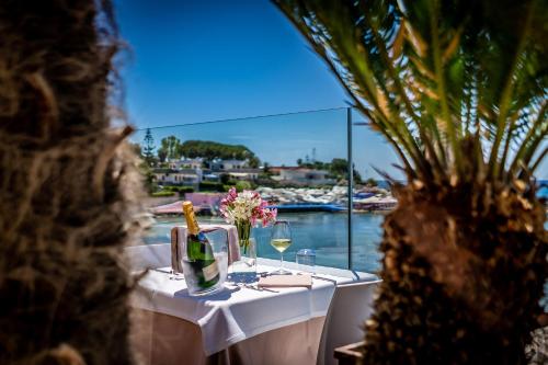 a table with a bottle of wine and glasses at White Bay in Fontane Bianche
