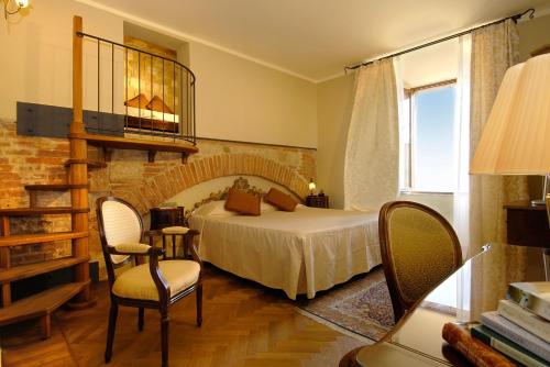 a bedroom with a bed and chairs in a room at La Locanda Di San Francesco in Montepulciano