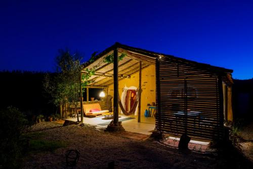 un pequeño cobertizo con porche por la noche en The Hobbit House - Montes da Ronha en Odemira