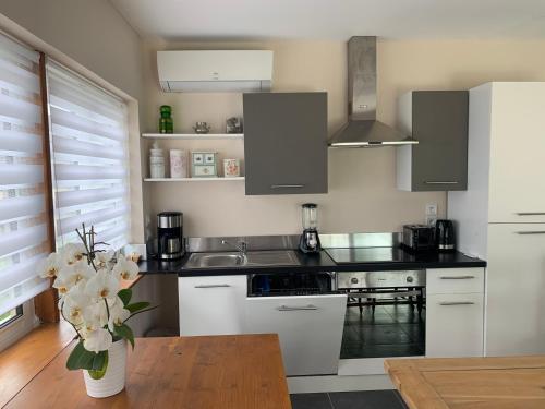 une cuisine avec des placards blancs et un vase de fleurs dans l'établissement La canadienne, à Assay