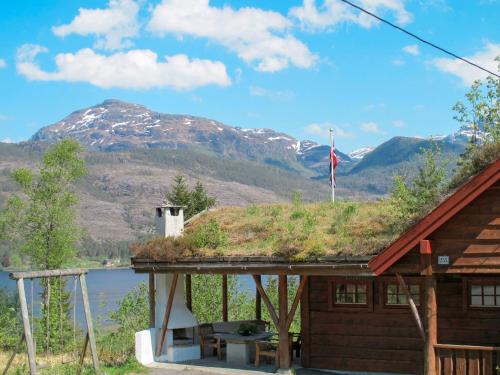 a cabin with a grass roof with a mountain in the background at Chalet Elisabeth by Interhome in Eikelandsosen