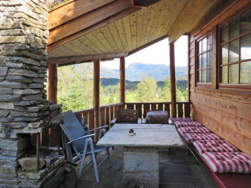 una veranda di una cabina con tavolo e panca di Chalet Anna - FJH661 by Interhome a Eikelandsosen