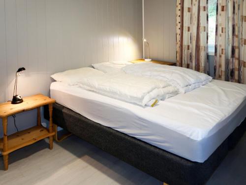 a large bed with white sheets and a side table at Holiday Home Fjordperlen by Interhome in Sørbø