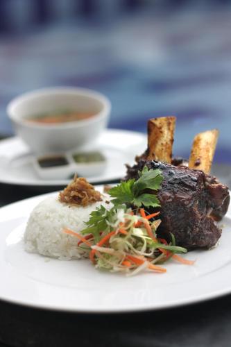a plate with meat and rice and a cup of soup at Vrata Hotel Yogyakarta in Kalasan