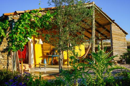 una casa amarilla con pérgola en un jardín en The Hobbit House - Montes da Ronha en Odemira