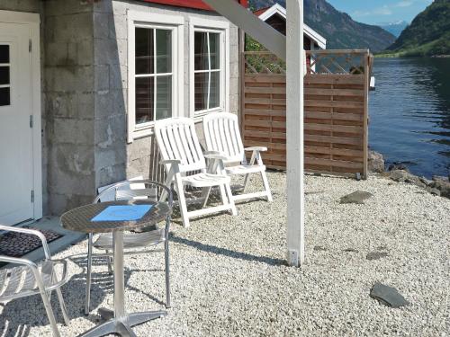 eine Gruppe von Stühlen auf einer Veranda neben dem Wasser in der Unterkunft Chalet Rødhette - FJS386 by Interhome in Gudvangen