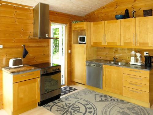 a kitchen with wooden cabinets and a sink and a stove at Chalet Smibakken - SOW016 by Interhome in Farsund
