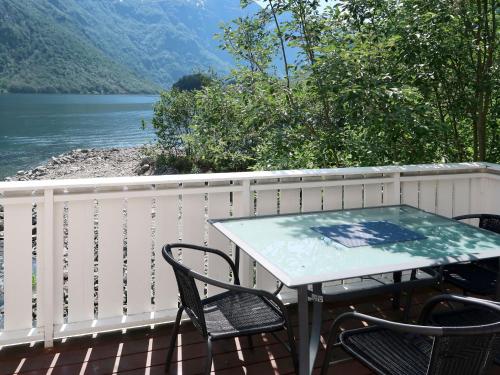 a table and chairs on a deck with a view of a lake at Chalet Kvitveis - FJS392 by Interhome in Gudvangen