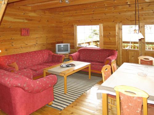 salon z czerwonymi kanapami i telewizorem w obiekcie Holiday Home August - FJS112 by Interhome w mieście Balestrand