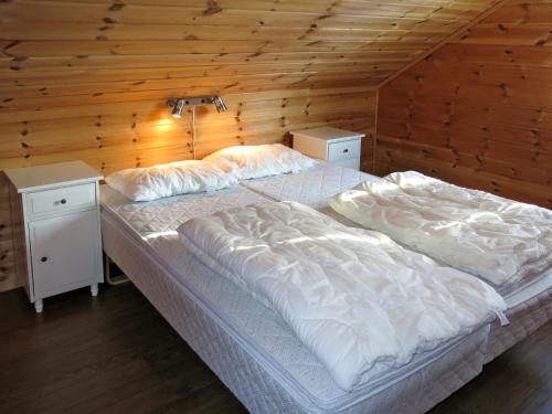 a large bed in a room with a wooden wall at Holiday Home Naudøyna by Interhome in Lyngdal