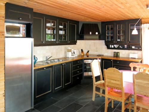 a kitchen with black cabinets and a table and a refrigerator at Holiday Home Naudøyna by Interhome in Lyngdal