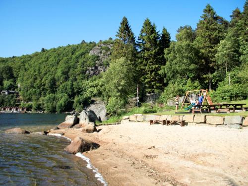 a beach with people sitting on a bench next to the water at Holiday Home Naudøyna by Interhome in Lyngdal