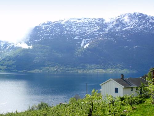 una casa sul lato di un lago con una montagna di Chalet Kårahuset - FJH408 by Interhome a Djønno