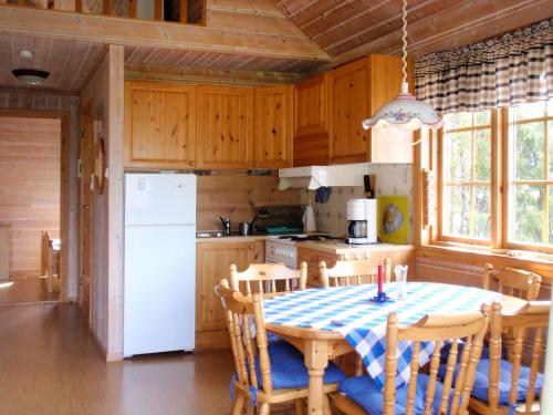 Il comprend une cuisine équipée d'une table et d'un réfrigérateur blanc. dans l'établissement Chalet Slåttenes - FJH415 by Interhome, à Naustflot