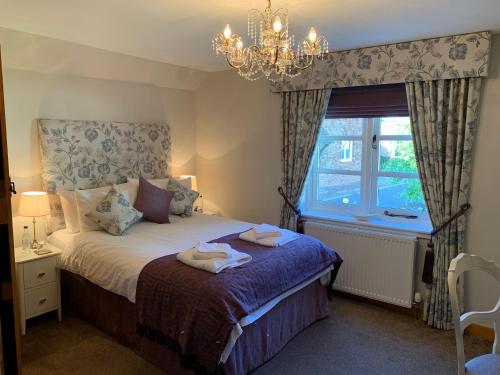 a bedroom with a bed with a chandelier and a window at Millstream Cottage B & B in Dunster