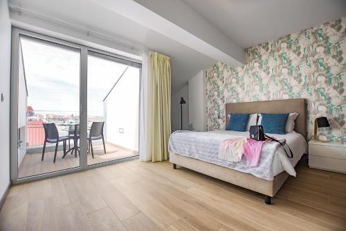 a bedroom with a bed and a balcony with a table at Terrazzos do Prado - Vista Ria de Aveiro in Costa Nova