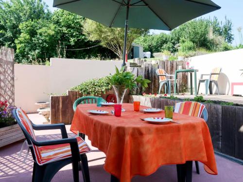- une table orange avec des chaises et un parasol sur la terrasse dans l'établissement Apartment Le Clos du Port 2 by Interhome, à Saint-Cast-le-Guildo