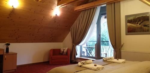 a bedroom with a bed and a window and a chair at Vila Lieska in Vysoke Tatry - Novy Smokovec