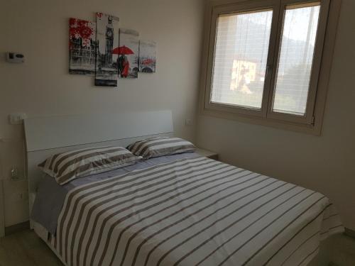 um quarto com uma cama com lençóis listrados e uma janela em Pisogne new apartment em Pisogne