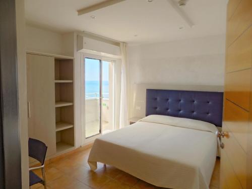 sypialnia z łóżkiem z niebieskim zagłówkiem i oknem w obiekcie Hotel Diplomatic w mieście Riccione