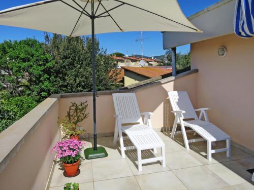 a patio with two chairs and an umbrella at Apartment Mansarda by Interhome in Rosignano Solvay