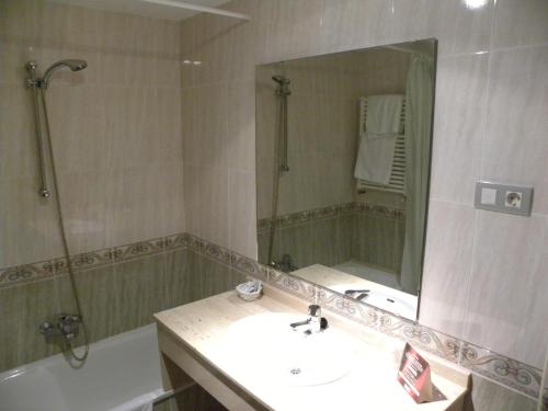uma casa de banho com um lavatório, uma banheira e um espelho. em Hotel Duque de Calabria em Manzanera