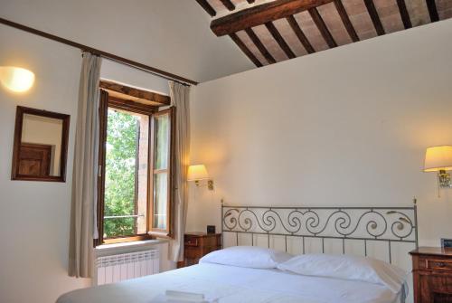 a bedroom with a white bed and a window at I Casali Della Ghisleria in Ospedalicchio