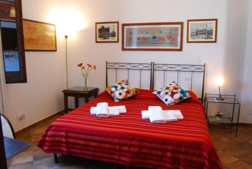 B&B Corte Barocca في ليتشي: غرفة نوم بسرير احمر عليه مناشف
