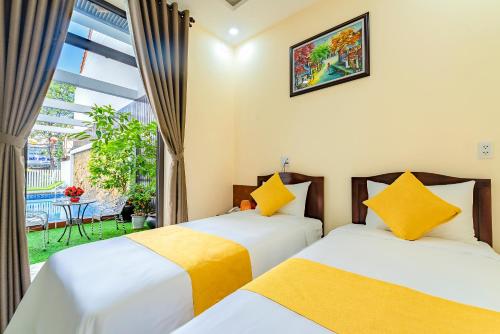 two beds in a room with a window at Green Hill Hotel in Hoi An