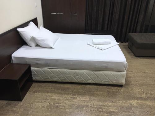 1 cama con sábanas blancas y almohadas en una habitación en Park and pool family room en Nesebar