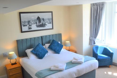 a bedroom with a large bed with blue pillows at Beach Green Hotel in Lancing