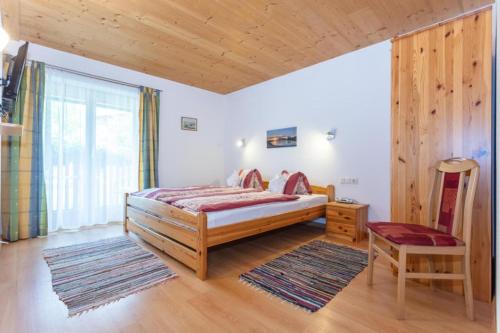 a bedroom with a bed and a chair and a window at Haus Machreich in Maria Alm am Steinernen Meer