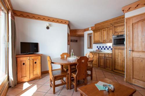 eine Küche mit Holzschränken und einem Tisch mit Stühlen in der Unterkunft Résidence Pierre & Vacances Premium Les Alpages de Reberty in Les Menuires