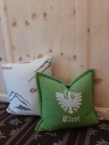a green pillow sitting next to a white pillow with an eagle on it at Haus Tirol Appartements in Ried im Oberinntal