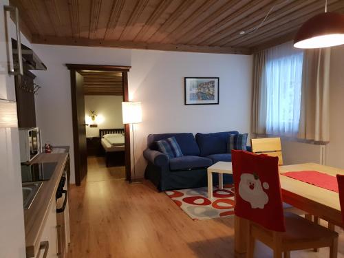 ein Wohnzimmer mit einem blauen Sofa und einem Tisch in der Unterkunft DEP GÄSTEHAUS Residenz in Neukirchen am Großvenediger
