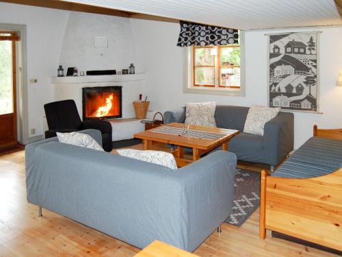 salon z kanapą, stołem i kominkiem w obiekcie Chalet Harge Sörgård - NAK 043 by Interhome w mieście Hammar