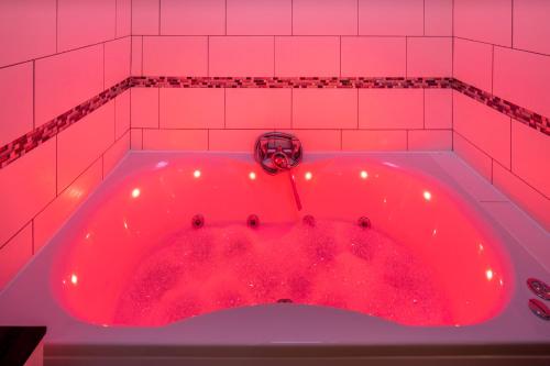 a red bath tub in a pink tiled bathroom at The Railway Inn - 3 Bed Luxury Stay in Milton Keynes