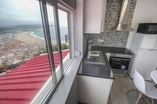 a kitchen with a large window and a view of the beach at Casa Ganga in Nazaré