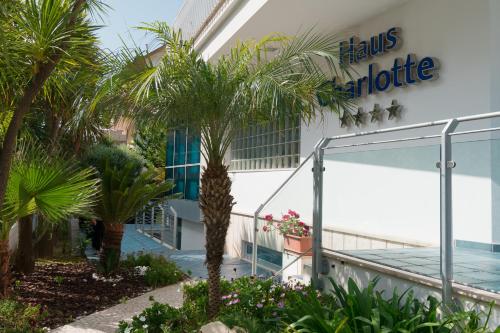 a hotel with palm trees in front of a building at Hotel Haus Charlotte in San Benedetto del Tronto