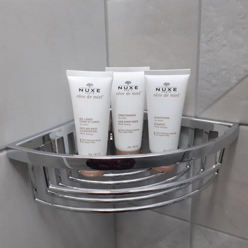 a metal shelf with three moisturizers on it in a bathroom at Le Charles V in Meursault